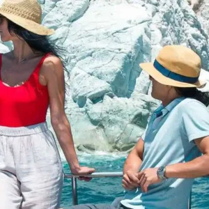 A couple relaxing on a Bali 4.1 catamaran while sailing near the striking white cliffs of Santorini’s White Beach in Greece.