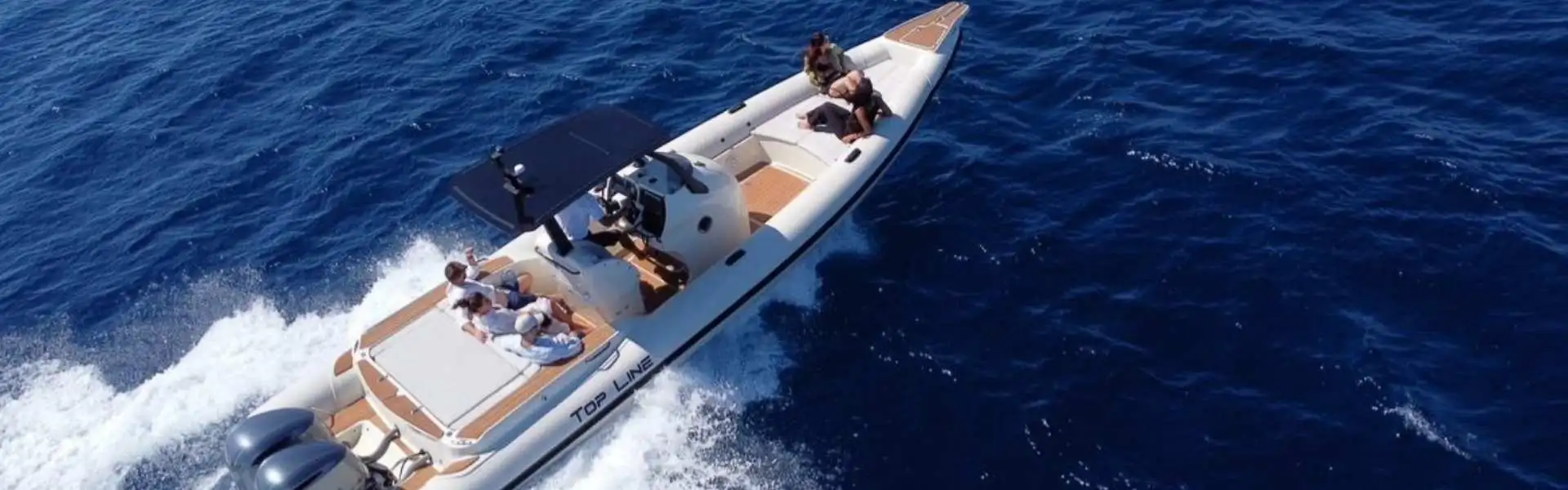 A white speedboat cruises across deep blue water off Mykonos, with several passengers relaxing on board.
