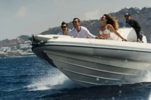 Guests enjoy a speedboat cruise around Mykonos on an AEGEANVIP charter, with the boat moving fast across the sea.